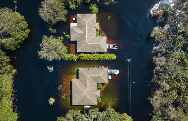Overhead shot of two homes surrounded by dirty floodwaters
